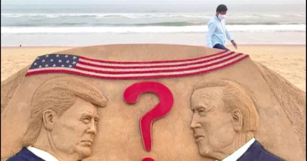Artist portrays the presidential trail in sand on an Indian sea slip